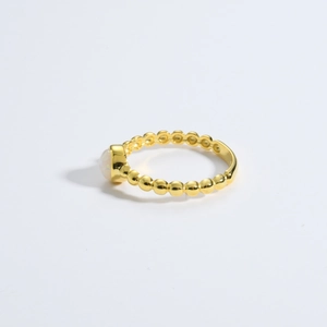 Macro detail of gold-plated chain ring featuring a white opal stone and beaded texture