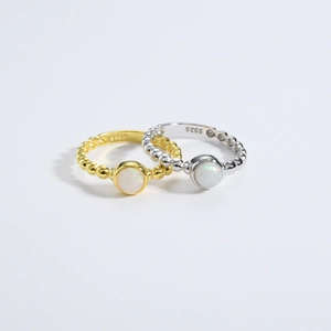 Macro view of gold and silver S925 beaded rings with white opal gemstone inlay