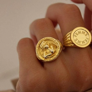 Primer plano de anillos de sello dorados con relieve de ángel y detalles grabados