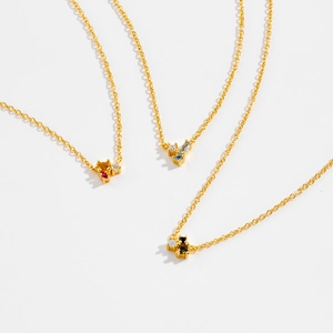 Tres elegantes collares dorados con colgantes de piedras preciosas de colores sobre blanco