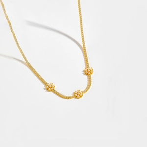 Macro shot of gold-plated necklace with sparkling zircon flowers and pearl centers