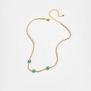 Detail of gold tennis chain necklace with blue floral charms and tiny pearls