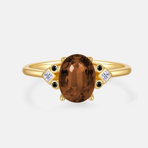 Detalle de anillo con gema marrón ovalada y diamantes sobre una banda de color oro
