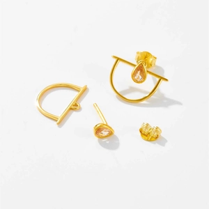 Detalle de pendientes geométricos dorados con piedras de champán en forma de gota y marco D
