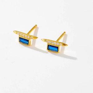 Detalle de pendientes geométricos dorados con zafiro azul rectangular y pavé de diamantes