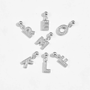 Makroaufnahme von silbernen Mikro-Pave-Zirkonia-Alphabet-Anhängern für DIY-Schmuck