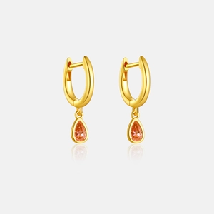 Detail of gold hoop earrings with sparkling orange pear-cut zirconia stone drops