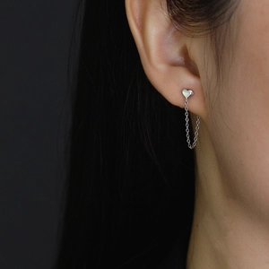 Dettaglio di orecchini a cuore in argento sterling 925 con eleganti catenine a croce pendenti