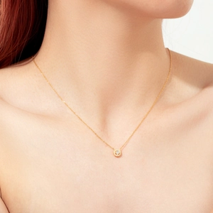 Dettaglio della collana in argento 925 dorato con ciondolo in zirconi indossata da una donna