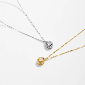 Dettaglio di ciondoli in zircone a goccia in finiture argento e oro con halo