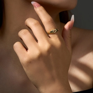 Close-up of a gold heart signet ring with micro-pave zircons worn on a finger