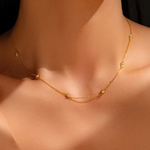 Close-up of a gold daisy necklace with zircon crystals on a female model's neck