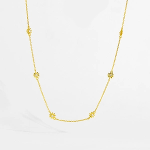 Detailed view of the delicate gold necklace featuring six small daisy charms with clear crystals