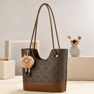 Brown monogram tote bag with leather handles and a plush monster charm on geometric stones