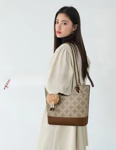 Detail shot of the brown monogram tote bag featuring a plush charm on the shoulder strap