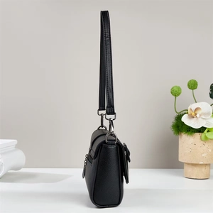Side view of black lychee grain leather crossbody bag with gunmetal hardware detail