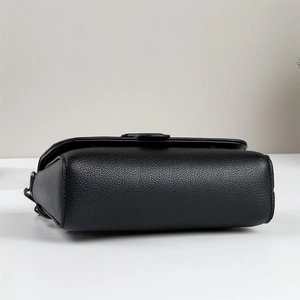 Detail view of black litchi grain leather shoulder bag with side metal hardware buckle