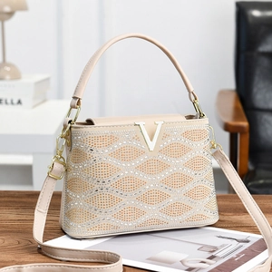 Striped handbag with shimmering rhinestones and gold V buckle on a wooden desk