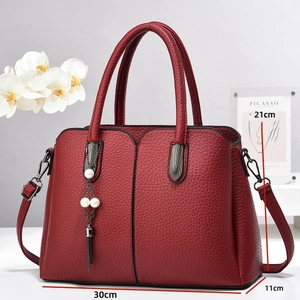 Vue détaillée du sac à main rouge avec pompon perlé et indications de dimensions