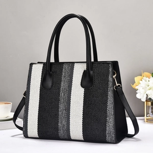 Detail view of woven striped tote bag with gold hardware and removable shoulder strap