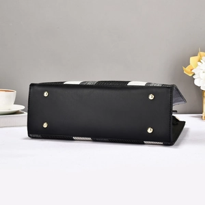 Detail view of handbag bottom with golden metal feet and black leather base material