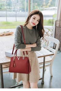 Détail d'un sac à main en cuir rouge grainé avec logo V doré et décoration à franges