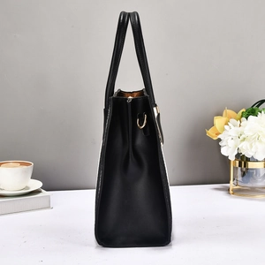 Close-up of black leather tote bag featuring gold D-ring hardware and sturdy handles