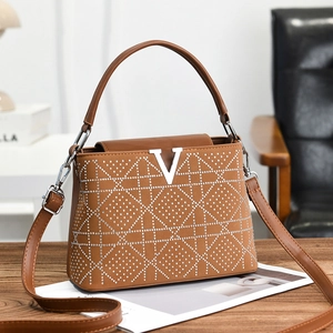 Brown plaid crossbody bag with V logo and crystal studs on a wooden desk setting