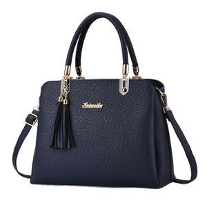 Dark blue pebbled leather handbag with gold logo and tassel accent on white background