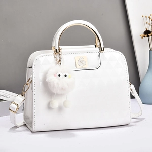 White quilted handbag with gold handle, bird logo, and fuzzy monster bag charm detail