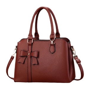 Deep red bow-accented lychee leather handbag with gold hardware shown from the front view
