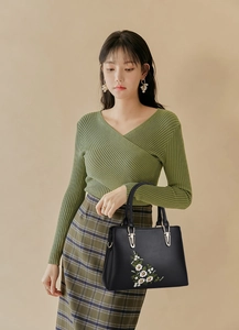 Sac à main noir élégant avec broderie florale porté par un mannequin en tenue de bureau