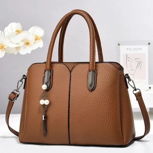 Détail d'un sac en cuir marron texturé avec breloque élégante en perles et franges