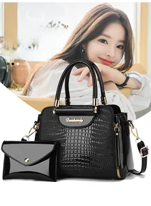 Detail of black crocodile texture handbag set with gold hardware and envelope pouch