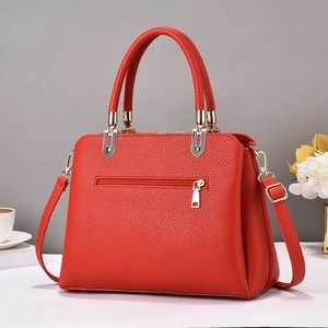 Détail du sac à main rouge en cuir grainé avec poche zippée et garnitures dorées