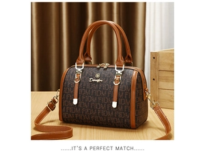 Close-up of brown monogram Boston bag with golden hardware and adjustable strap on a wood table