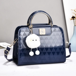 Detail of dark blue patent leather bag with embossed triangles and golden bird logo