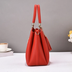 Détail d'un grand sac cabas en cuir rouge avec pompon élégant et finitions dorées