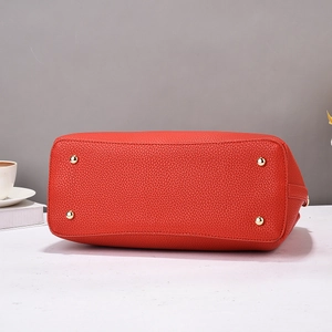 Détail du fond d'un sac à main en cuir rouge avec quatre clous de protection dorés