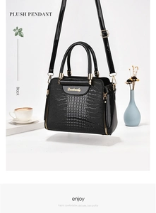 Detail showing crocodile pattern texture and golden logo on black women's shoulder bag