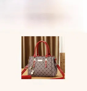 Close-up of stylish M-letter printed tote bag with red handle and pearl pendant charm
