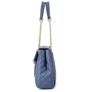 Detail of blue quilted shoulder bag featuring gold chain strap and stitching