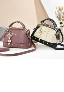 Detail of lychee pattern leather handbag with pearl charm and gold rivet accents