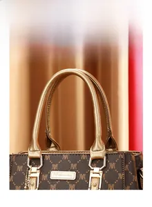 Detail of reinforced champagne leather handles and monogram pattern on brown handbag