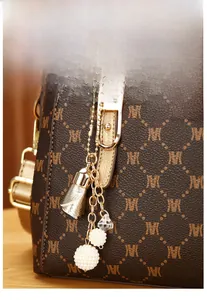 Detailed view of dark brown monogram handbag with golden hardware and fringe tassel charm