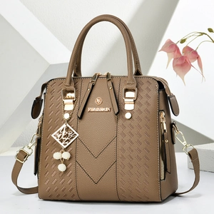 Detail of brown faux leather Boston bag with V-shaped texture and pearl metal charm