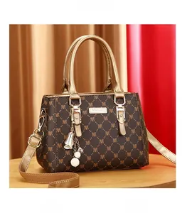 Detailed view of fashion handbag with M-pattern monogram, gold handles, and pearl charm
