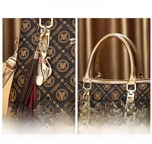 Détail d'un sac à main imprimé monogramme avec breloque chat dorée et pompon décoratif
