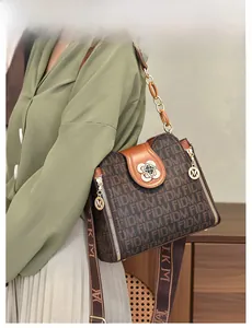 Détail du sac à bandoulière en jacquard avec fermoir fleur dorée porté par un mannequin