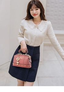 Detailed view of pink textured leather handbag featuring elegant pearl and gold chain charm